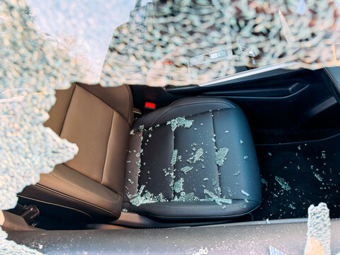 Car interior view through broken window with glass shards.