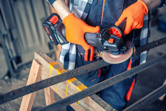A man cuts metal using an angle grinder. Many sparks