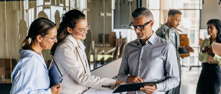 Black, white, asian manager reviewing contracts with colleague