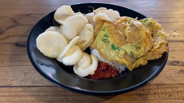 Indonesian fried egg omelette with rice and crispy crackers