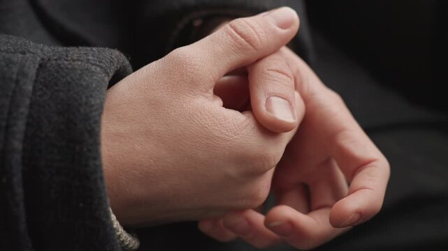 Closeup caucasian creator hands fidgeting, wool sleeve visible, thumb rubbing nail, knuckles tense, subtle motion during quiet reflection, roles shifting from designer to writer to photographer, mood
