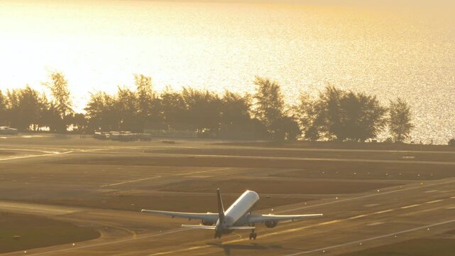 Passenger airplane departure at Phuket airport, yellow sunset light.
