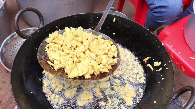 Traditional Indian mirchi bajji deep frying in a large pan of bubbling golden oil for authentic street food.
