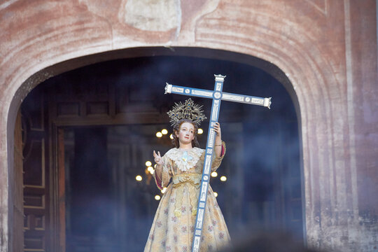 Religious statue holding a cross at church entrance during Semana Santa procession in Granada, Spain, with smoke and soft light. Editorial use only