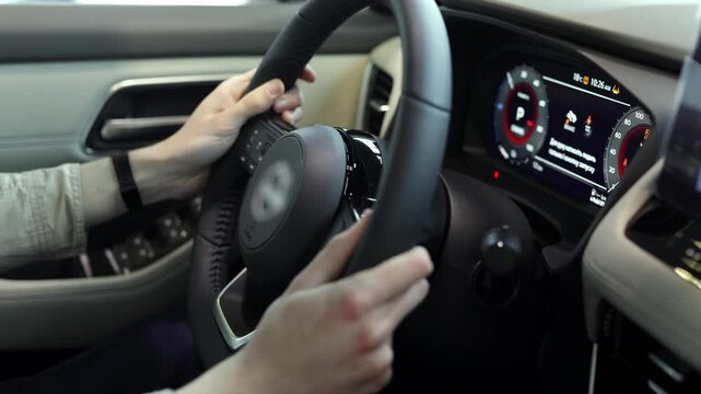 Close up of steering wheel and hands in modern car interior. Vehicle control concept.