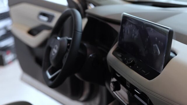 Interior view of modern vehicle dashboard featuring steering wheel and touchscreen display, showcasing sleek design and advanced technology in a contemporary automotive setting