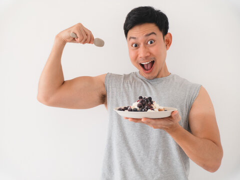 Athletic individual displaying biceps with nutritious snack in studio