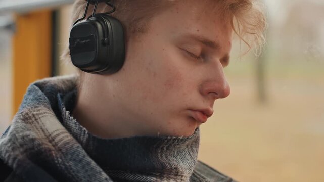 Creative individual immersed in musical creation during ride. Young composer lost in sound while traveling through park. Passionate artist crafts melodies on bus with headphones on and eyes closed
