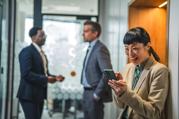 Fototapeta premium Businesswoman laughing while using smart phone in office