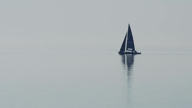 Sailboat sailing on open ocean with white sails billowing in wind, embarking on adventure and freedom voyage.

