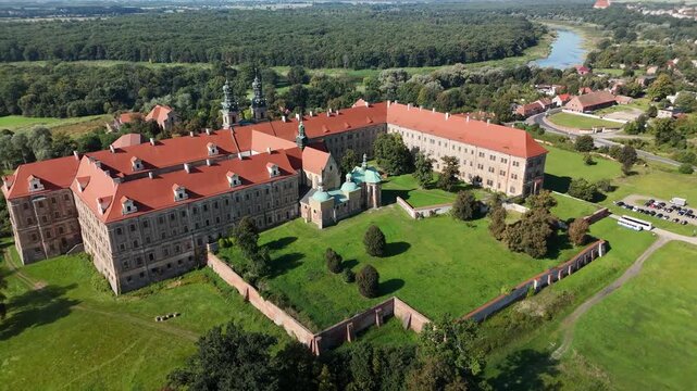 Aerial drone view of Cistercian Abbey in Lubiąż, Lower Silesia, Poland, surrounded by lush green forests, river, and scenic countryside landscape, historic monastery and cultural heritage site