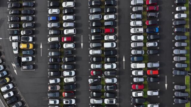 Aerial view of a densely packed car park, a mosaic of black, white, and grey cars, interspersed with splashes of red, yellow and blue, Porto, Portugal.