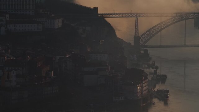 Aerial view of the Dom Luis I Bridge along the Douro River, with buildings lining the riverbank, Porto, Portugal.