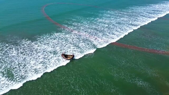 Cox's Bazar, Bangladesh - 08 April 2026: Aerial view of a boat resting on the sandy shore meeting the turquoise sea with foamy white waves.