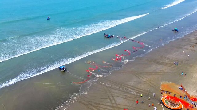 Cox's Bazar, Bangladesh - 08 April 2026: Aerial view of fishing nets spread on the beach, with people and boats visible against the backdrop of blue ocean waves.