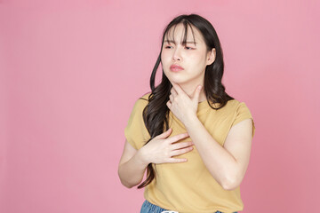 Obraz premium Young woman holding throat in discomfort against pink background
