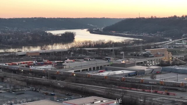Aerial view of a trainyard, the Ohio River, and surrounding buildings under a colorful sky, Cincinnati, Ohio, United States.