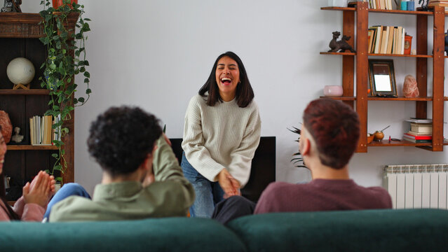 Group of friends laughing and playing charades at home