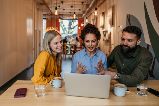 Business individuals discussing ideas around laptop during meeting