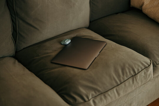Laptop and earbuds resting on a comfortable sofa cushion