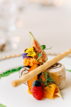 Gourmet appetizer with fresh fruits, edible flowers, and a breadstick