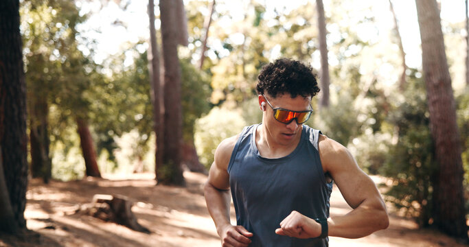 Fitness, smart watch and runner with man in forest for workout stats, distance tracking and health. Exercise performance, wellness and tech with person outdoor for speed monitor and stopwatch