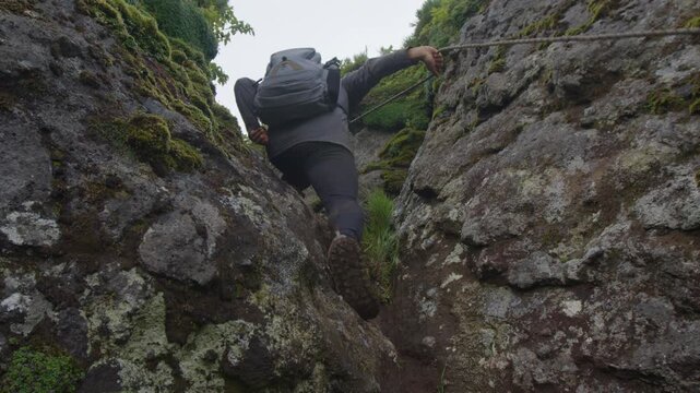 Hiker climbs on the tricky trail in the wild volcanic area on Kunashir Island. Russia