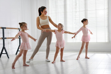 Naklejka premium Ballet teacher having class with children in dance studio