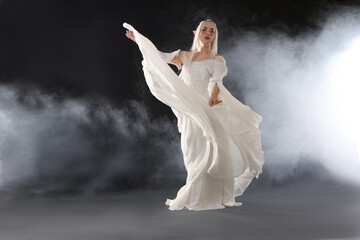 Naklejka premium Beautiful girl dressed as elf on black background with smoke