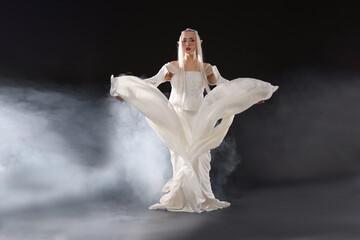 Naklejka premium Beautiful girl dressed as elf on black background with smoke