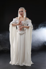 Naklejka premium Beautiful girl dressed as elf on black background with smoke