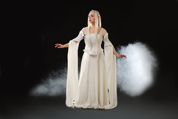 Naklejka premium Beautiful girl dressed as elf on black background with smoke