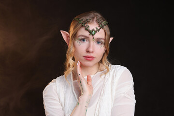 Naklejka premium Beautiful girl dressed as elf on black background with smoke