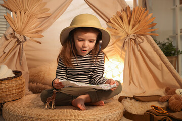 Little girl with drawing of map near wigwam at home © New Africa