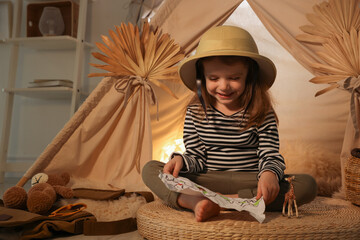 Little girl with drawing of map near wigwam at home. Space for text © New Africa