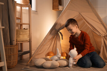 Little boy playing with toys near wigwam at home © New Africa