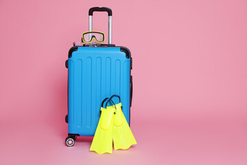 Blue suitcase, flippers and diving mask on pink background. Space for text © New Africa