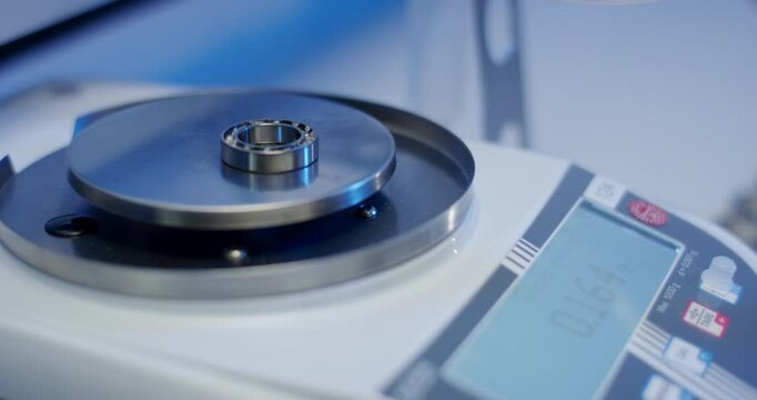Steel ball bearing placed on a precision electronic digital scale in a laboratory or industrial setting
