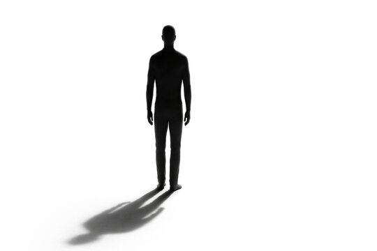 Black silhouette of a standing man facing away while casting a long shadow on a white floor surface