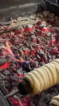 Kurtos chimney cake preparation Hungarian Czech sweet dough rolled over spit traditional baked dessert street food