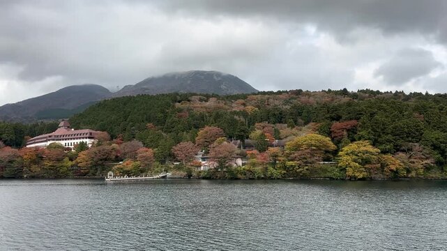 Scenic autumn landscape in Japan with colorful foliage on trees lining the shore of a Ashi Lake,  tc01