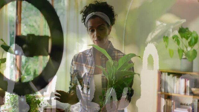 Vertical video: Greeting cam woman with headband showing plant tips at home lifting it by ringlight