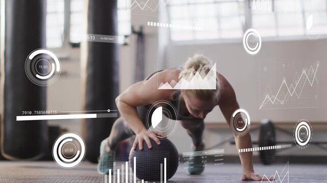 Vertical video: Doing athlete in leggings pushing on medicine ball in gym, timer tracking metrics