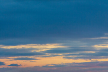 Obraz premium Soft blue and yellow sunset sky with layered clouds