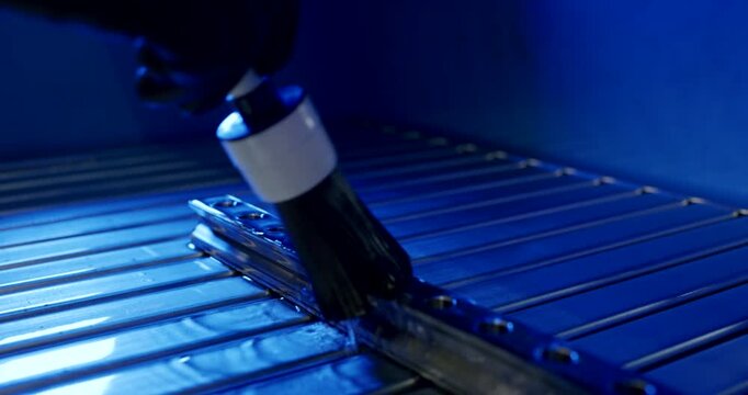 Technician cleaning a metal component with a brush in a professional industrial laboratory