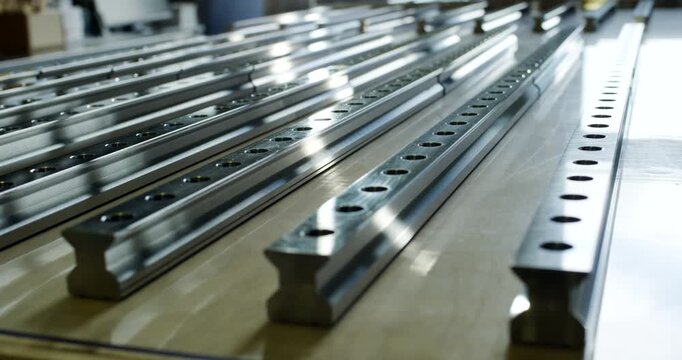 Polished steel linear guide rails with mounting holes arranged in rows for industrial machinery