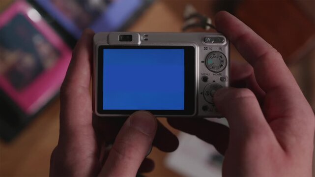 Horizontal top view of a classic silver digital camera. The blank blue screen is ready for a screen replacement mockup, display of interface, or media content.