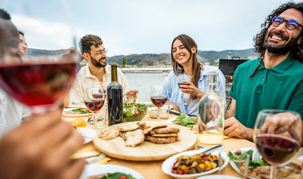 Happy friends having barbecue dinner party at home balcony  - Young people enjoying lunch break at restaurant terrace