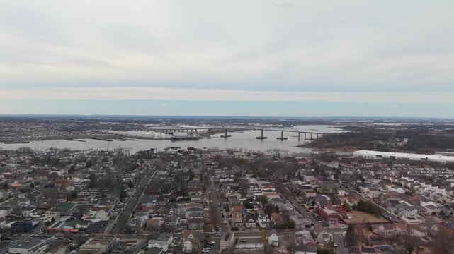 Aerial perspective over the historic town of perth amboy, new jersey, showing residential homes and streets with the victory bridge spanning the raritan river on a cloudy winter day