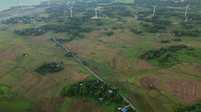 Picturesque aerial flyover of terraced farmlands with wind turbines and rural highway road - Guimaras Island, Philippines